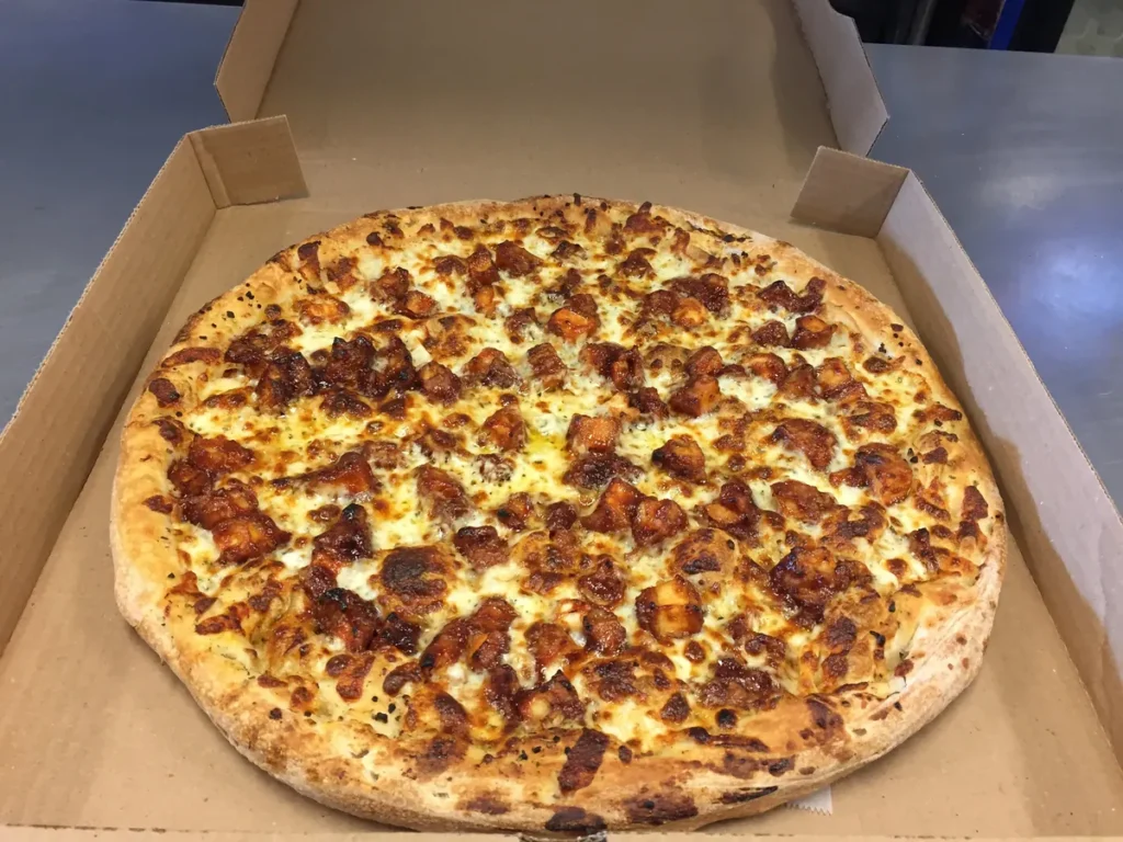 BBQ chicken pizza on a garlic and olive oil base with mozzarella and oregano, in an open pizza box
