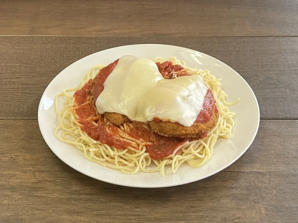 Chicken parm with melted mozzarella and marinara over spaghetti