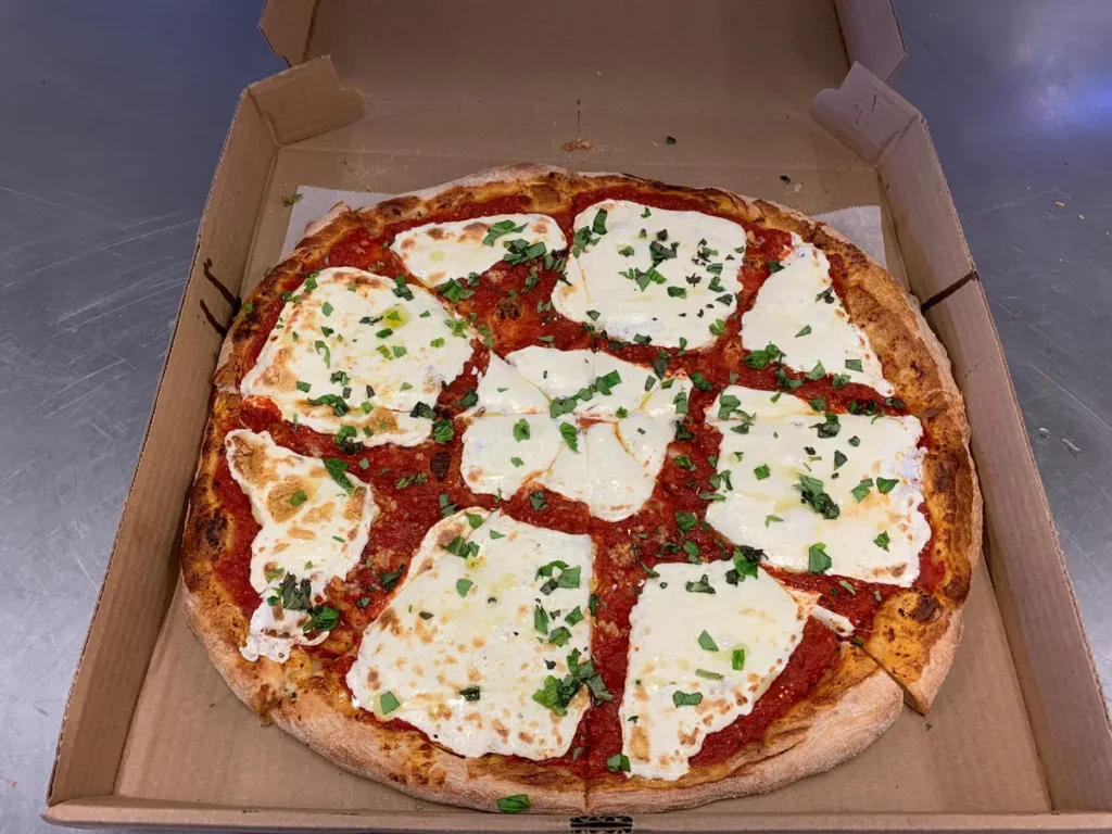 Queen Margherita pizza with slices of fresh mozzarella and fresh basil, cut into squares