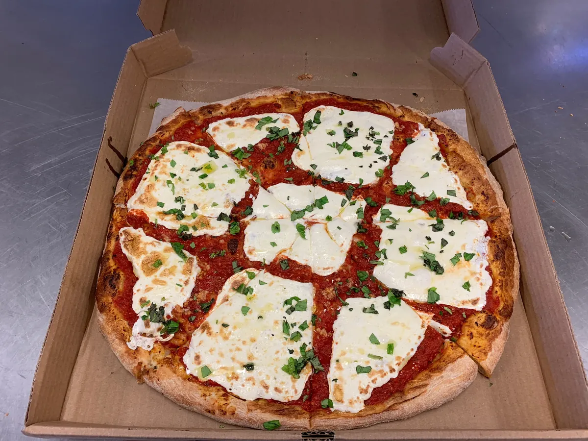 Queen Margherita pizza with slices of fresh mozzarella and fresh basil, cut into squares