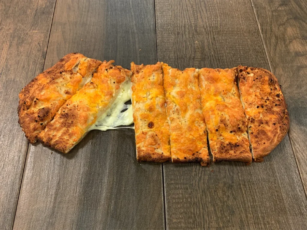 Stuffed cheesy garlic bread cut into strips with melted cheese pulling apart