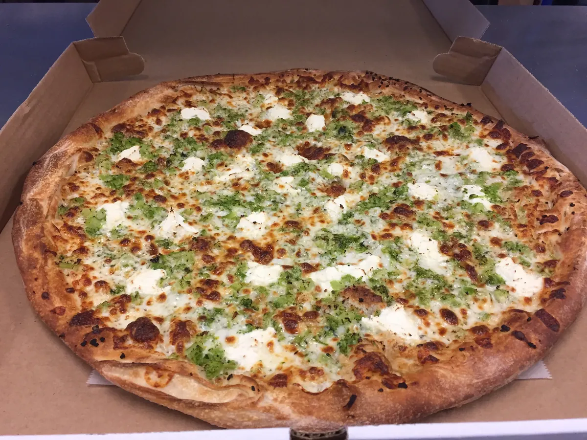White pizza with broccoli and dollops of ricotta on a garlic and olive oil base